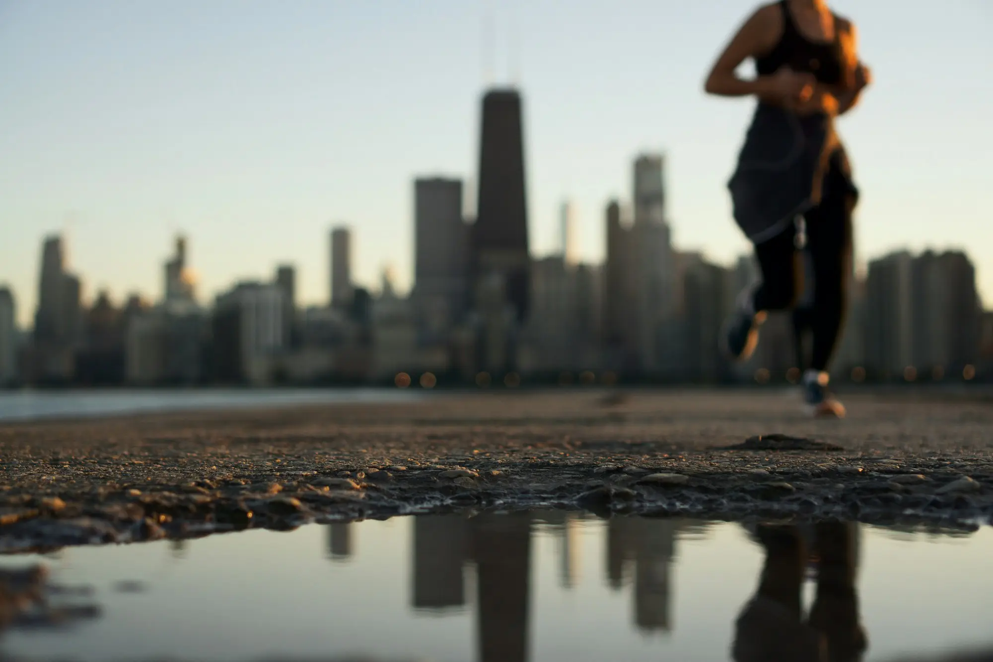 A runner on the lakefront at golden hour, city skyline behind