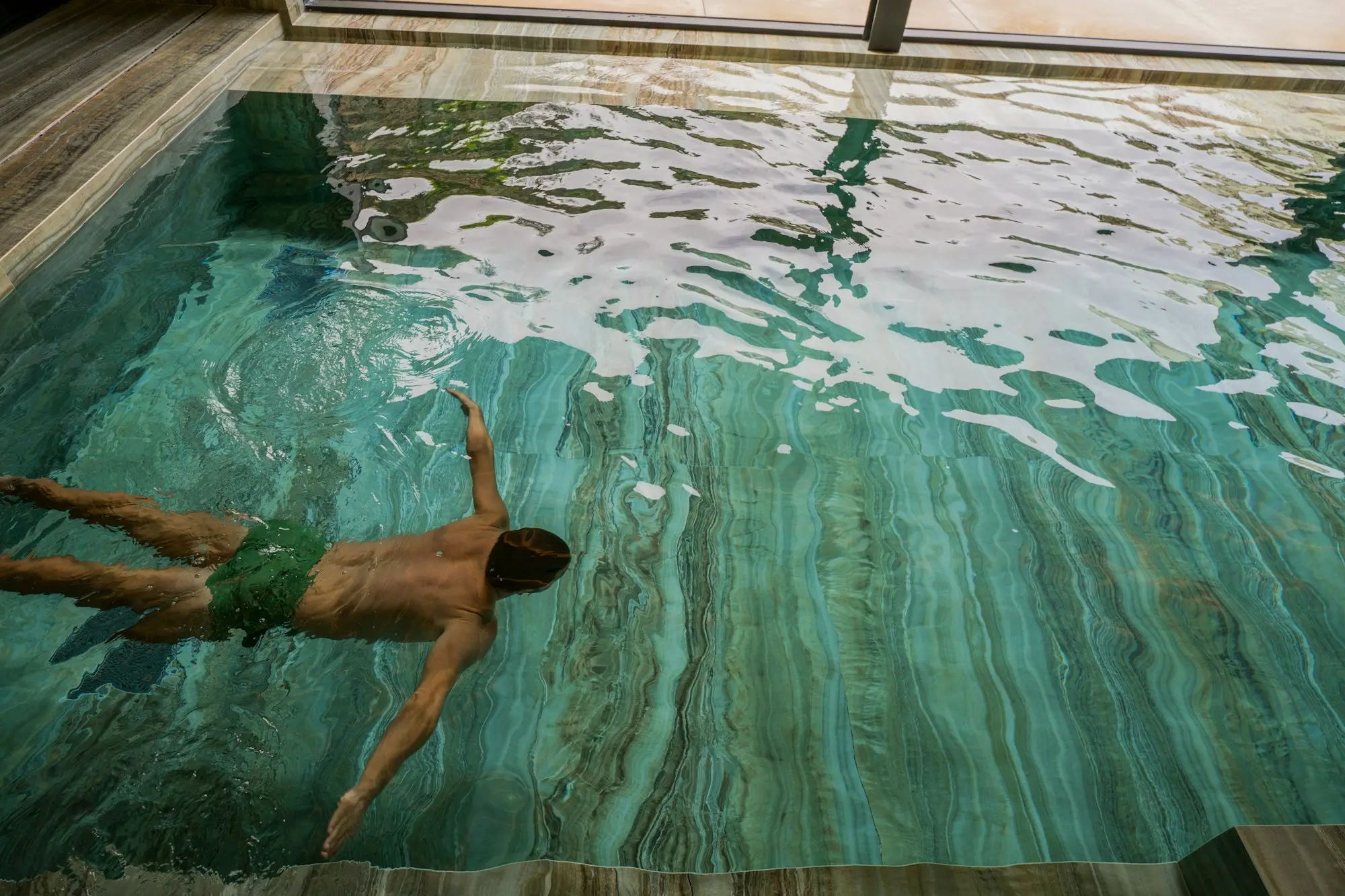 A swimmer gliding through a green-tiled pool